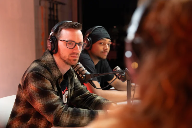 Twee mannen in een podcast studio met koptelefoons op en microfoons